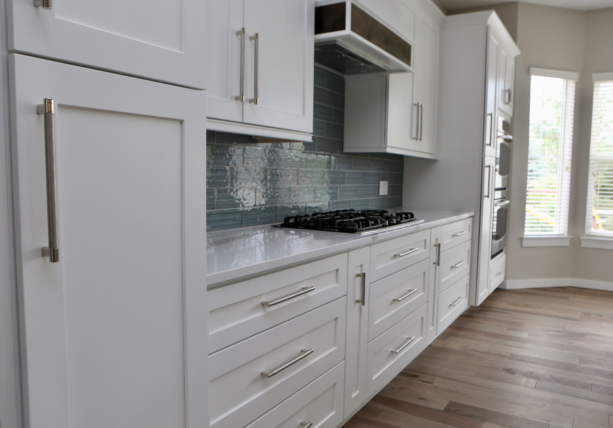 White shaker-style kitchen cabinets with dark backsplash